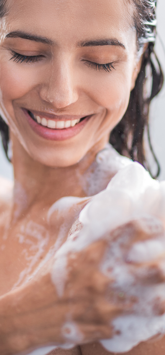 immagine ragazza che sorride, si mette la schiuma per detergere il corpo